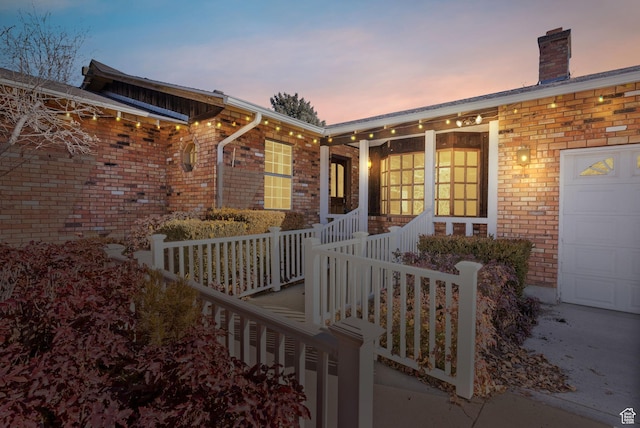 exterior entry at dusk featuring a garage and covered porch