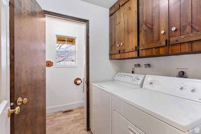 clothes washing area with independent washer and dryer, cabinets, and light wood-type flooring