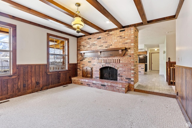 unfurnished living room with a fireplace, a healthy amount of sunlight, and beam ceiling