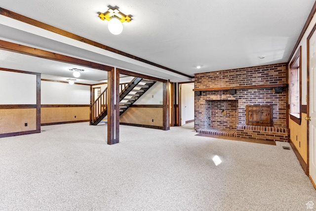 basement featuring light carpet, a fireplace, wooden walls, and a textured ceiling