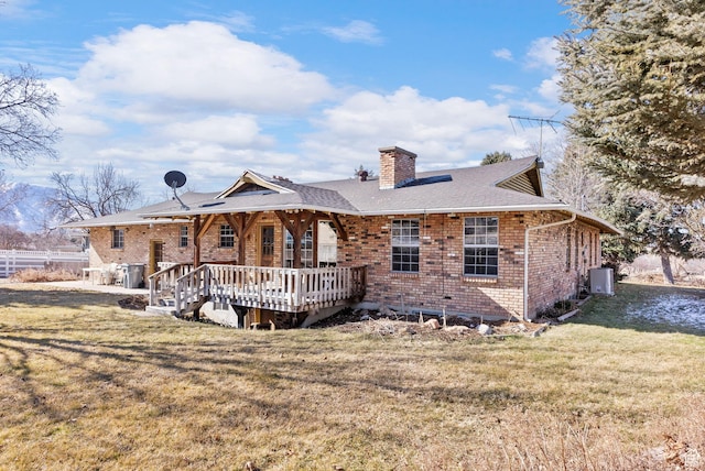 rear view of property with a wooden deck and a lawn
