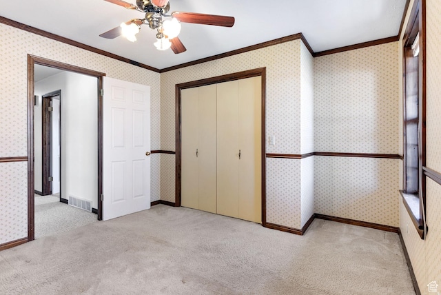 unfurnished bedroom with crown molding, a closet, ceiling fan, and light carpet