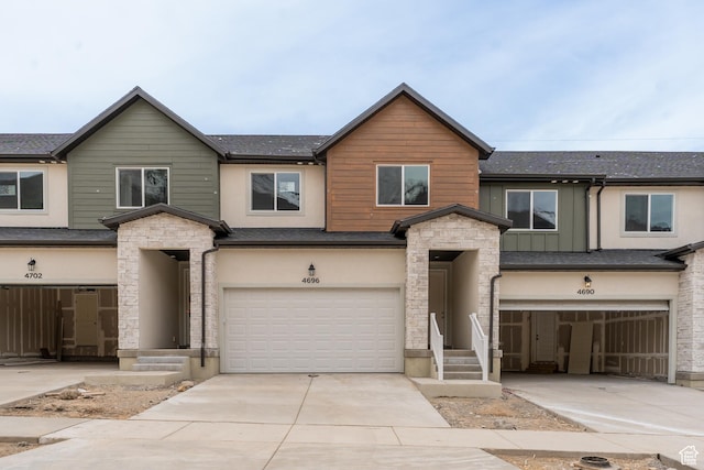 4696 S Alder Dr Unit 214, Mapleton, UT 84664 - view of front facade with driveway, an attached garage, stone siding, and stucco siding