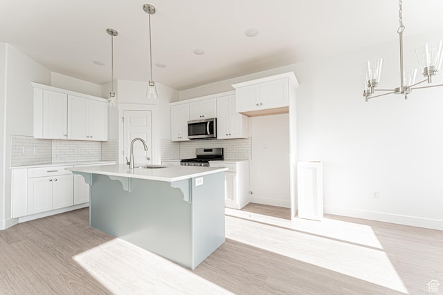 4696 S Alder Dr Unit 214, Mapleton, UT 84664 - kitchen featuring stainless steel appliances, a sink, light wood-style floors, decorative backsplash, and white cabinetry