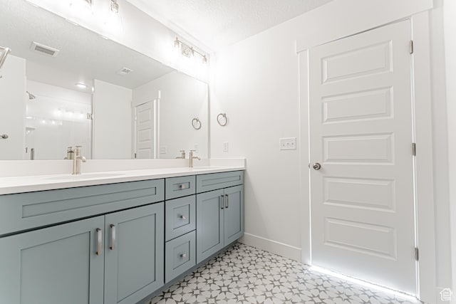 4696 S Alder Dr Unit 214, Mapleton, UT 84664 - bathroom featuring double vanity, tile patterned floors, baseboards, a textured ceiling, and a shower with door