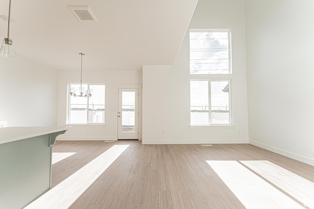 4696 S Alder Dr Unit 214, Mapleton, UT 84664 - unfurnished living room featuring a chandelier, light wood-style flooring, baseboards, and plenty of natural light