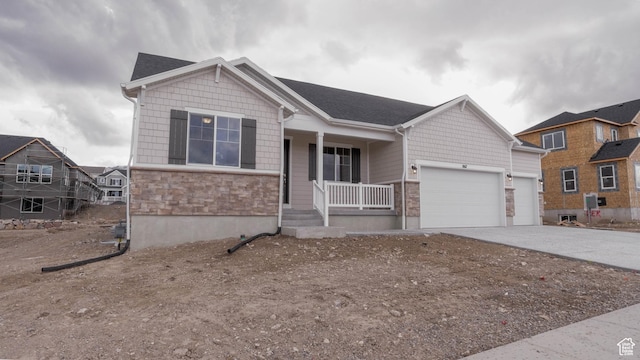 ranch-style house with stone siding, a porch, concrete driveway, and a garage
