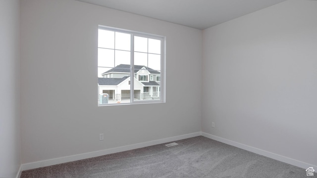 unfurnished room featuring baseboards, visible vents, and carpet