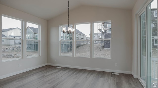 unfurnished dining area with lofted ceiling, baseboards, a chandelier, visible vents, and wood finished floors