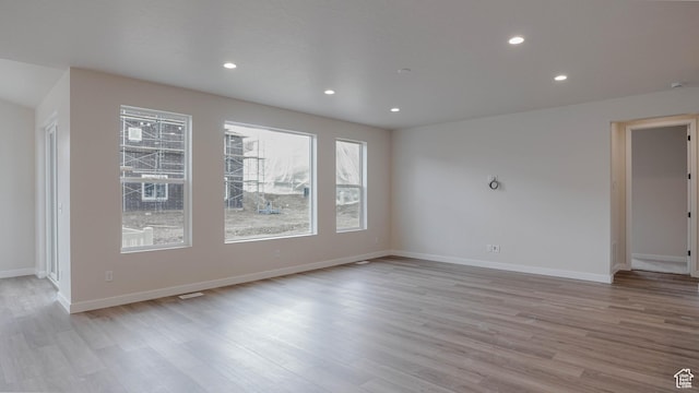 spare room featuring light wood finished floors, baseboards, and recessed lighting