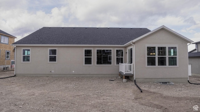 rear view of property with stucco siding and a shingled roof
