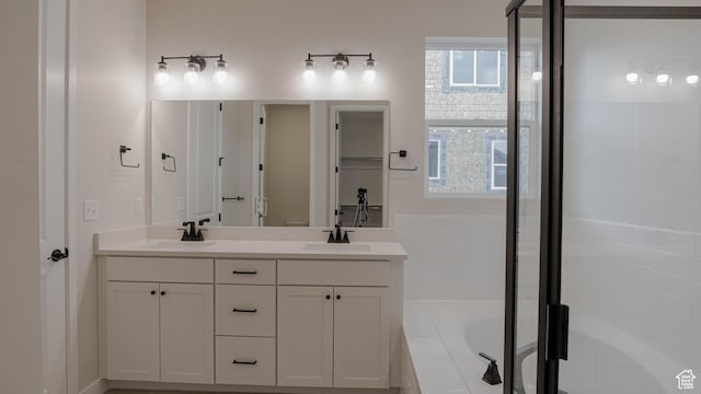 bathroom featuring a bath, double vanity, a sink, and a stall shower