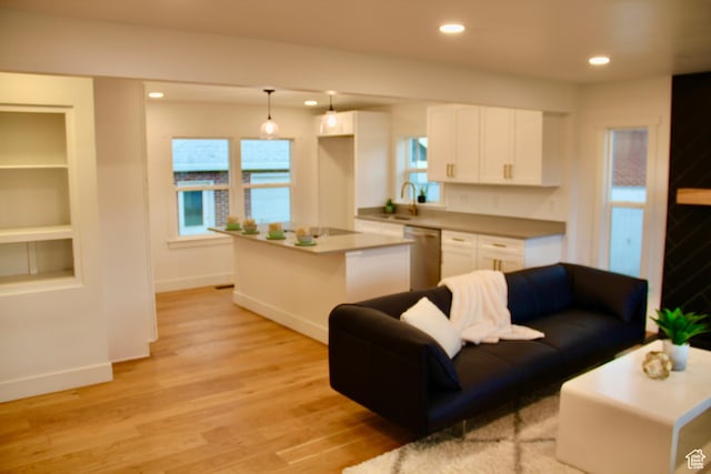 living room with sink, built in shelves, and light wood-type flooring