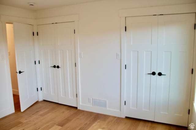 unfurnished bedroom with multiple closets and light hardwood / wood-style floors