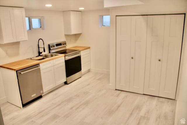 kitchen featuring light wood-type flooring, stainless steel appliances, sink, and white cabinets