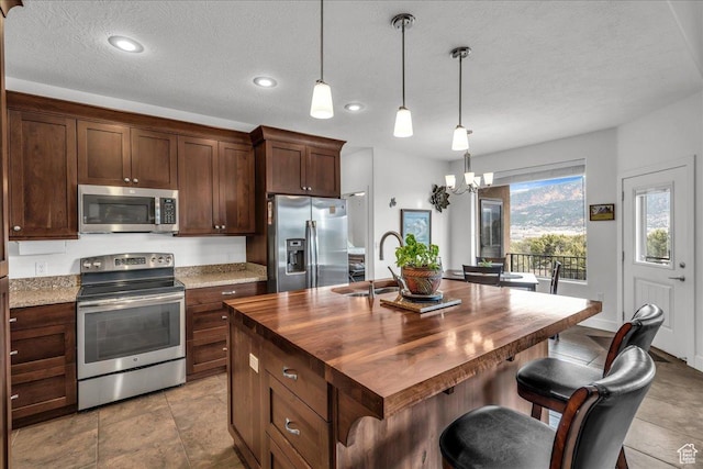 23 S 1200 W, Kanarraville, UT 84742 - kitchen featuring sink, butcher block countertops, hanging light fixtures, a center island with sink, and appliances with stainless steel finishes