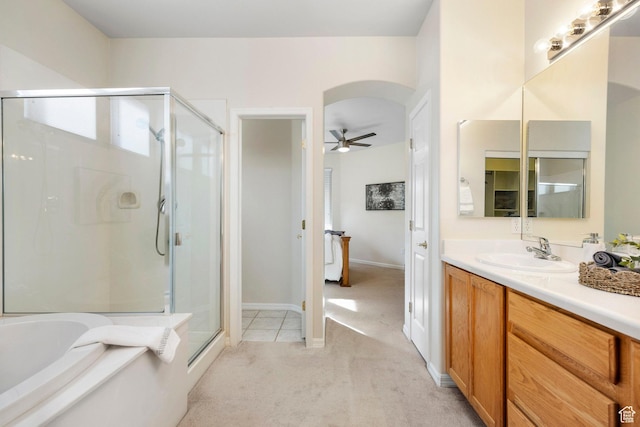 bathroom with a stall shower, a bath, vanity, a ceiling fan, and baseboards