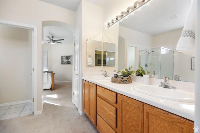 bathroom featuring ceiling fan, a shower stall, double vanity, baseboards, and tile patterned floors