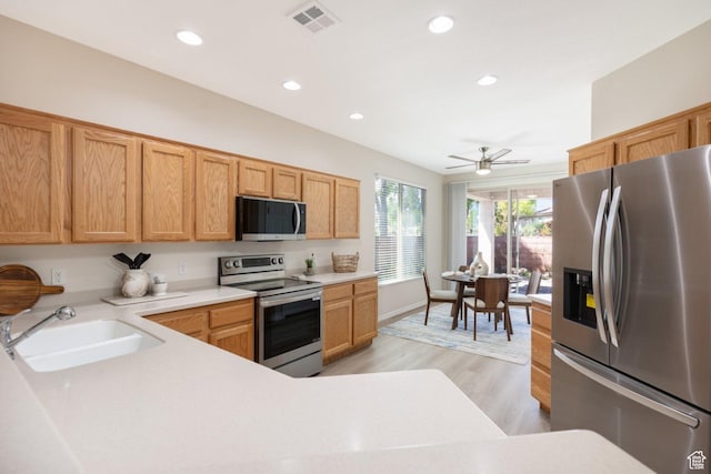 kitchen featuring appliances with stainless steel finishes, a sink, light countertops, light wood-type flooring, and recessed lighting