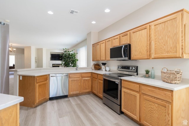 kitchen with appliances with stainless steel finishes, a sink, a peninsula, a chandelier, and open floor plan