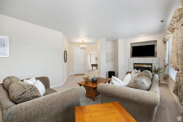 living area featuring light colored carpet, a fireplace, a chandelier, and baseboards