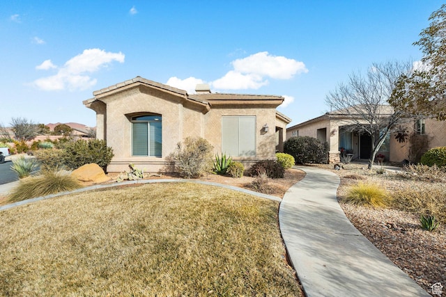 view of front of home featuring stucco siding, a front lawn, and a tiled roof