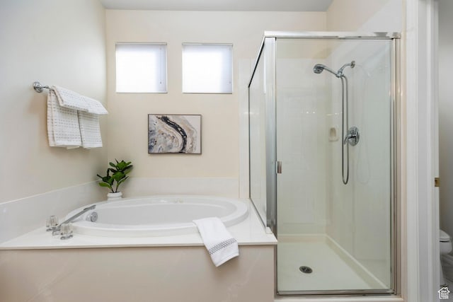 bathroom with a stall shower, a bath, and toilet