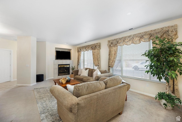 living room featuring light carpet, baseboards, and a tiled fireplace