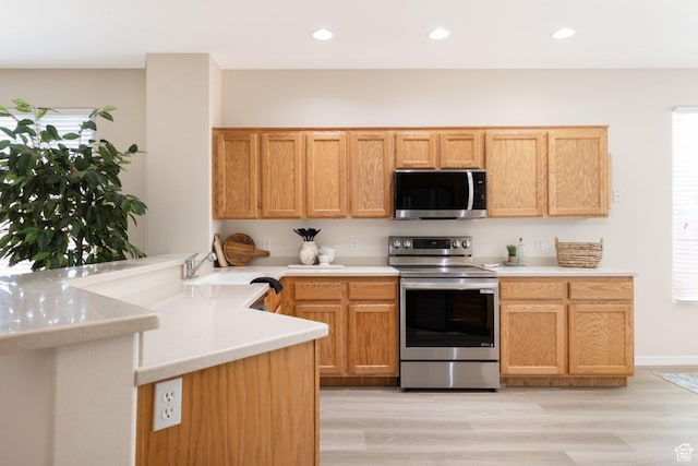 kitchen with stainless steel appliances, a peninsula, light countertops, and recessed lighting