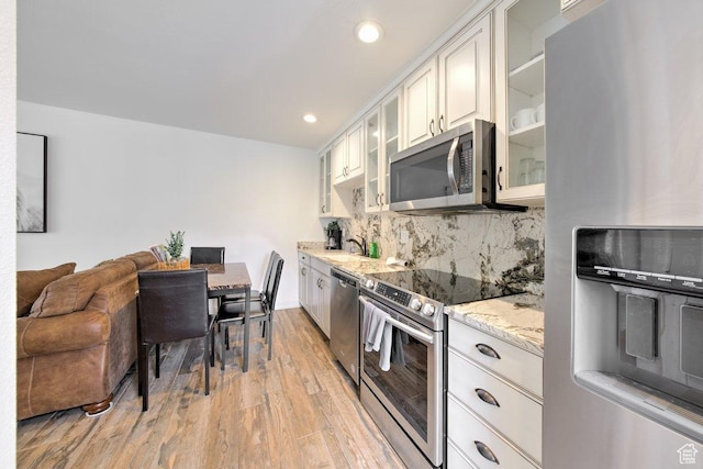 286 W Eagles Roost St Unit D-101, Brian Head, UT 84719 - kitchen with white cabinetry, light stone counters, light wood-type flooring, stainless steel appliances, and decorative backsplash