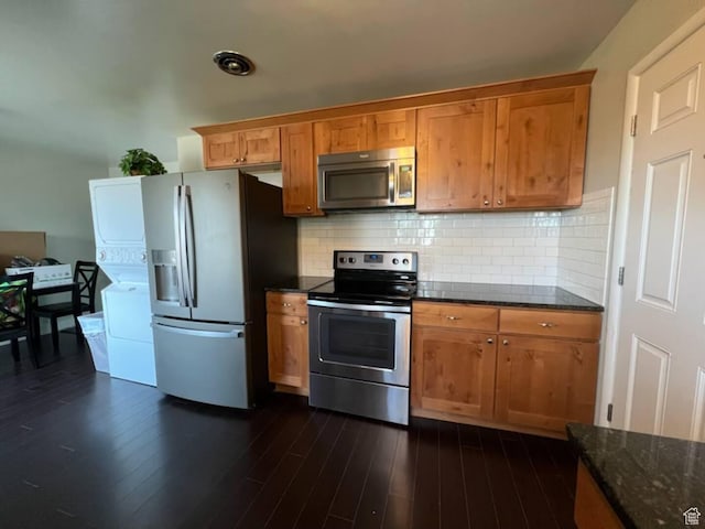 127 Mason Ln, North Salt Lake, UT 84054 - kitchen with dark wood-type flooring, stacked washing maching and dryer, dark stone countertops, appliances with stainless steel finishes, and tasteful backsplash