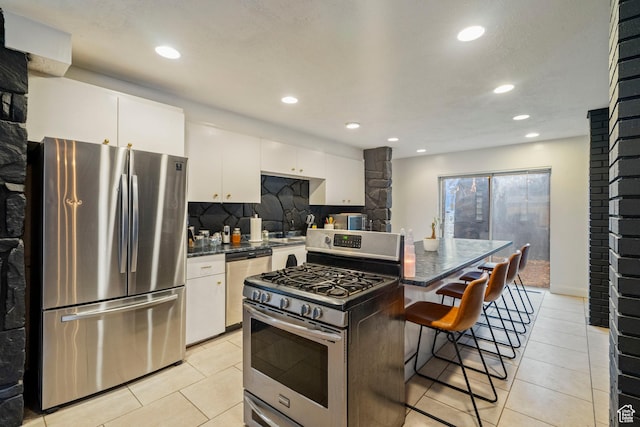 1078 Sumac Dr, Logan, UT 84321 - kitchen with a kitchen bar, white cabinetry, tasteful backsplash, a kitchen island, and stainless steel appliances