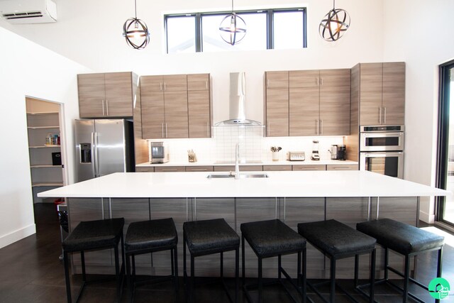 145 Crimson Cliffs Dr, Moab, UT 84532 - kitchen featuring decorative light fixtures, a wall mounted AC, appliances with stainless steel finishes, a kitchen breakfast bar, and wall chimney range hood