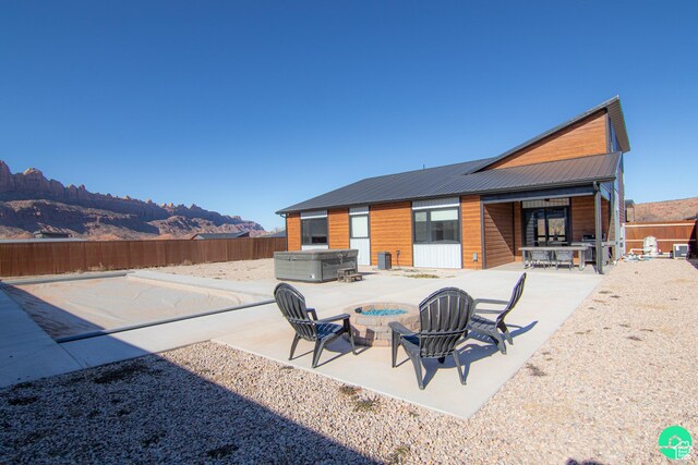 145 Crimson Cliffs Dr, Moab, UT 84532 - rear view of property featuring a hot tub, a mountain view, a patio area, and an outdoor fire pit
