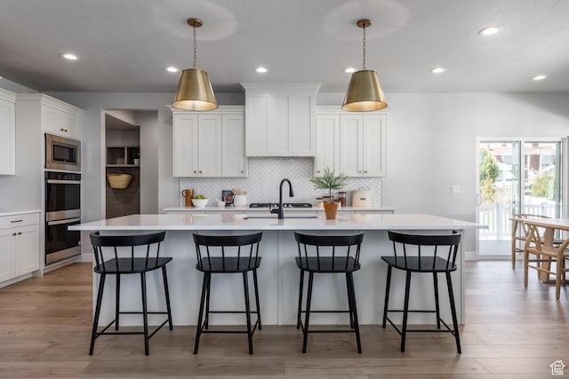 7288 W Hall Crossing Dr S, Herriman, UT 84096 - kitchen featuring appliances with stainless steel finishes, light countertops, tasteful backsplash, a center island with sink, and white cabinetry