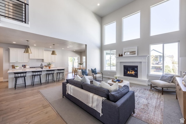 7288 W Hall Crossing Dr S, Herriman, UT 84096 - living area with a towering ceiling, light wood-style flooring, a tile fireplace, and recessed lighting