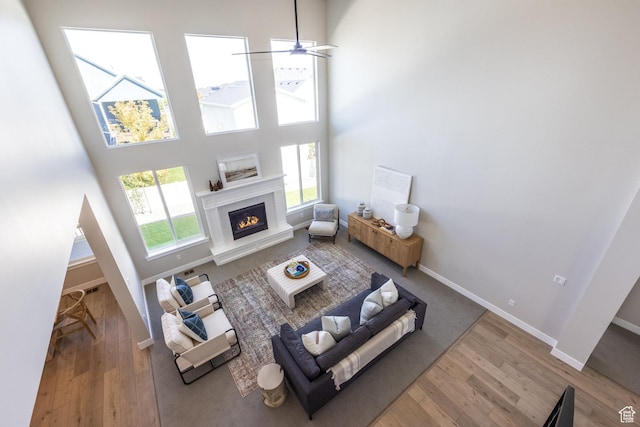 7288 W Hall Crossing Dr S, Herriman, UT 84096 - living area with a premium fireplace, wood finished floors, a ceiling fan, and a towering ceiling