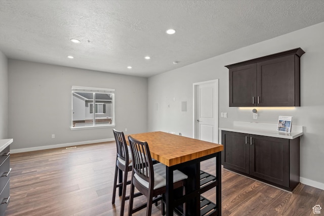 dining room featuring recessed lighting, a textured ceiling, baseboards, and dark wood finished floors