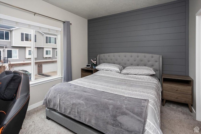 bedroom with baseboards, wood walls, carpet flooring, and a textured ceiling