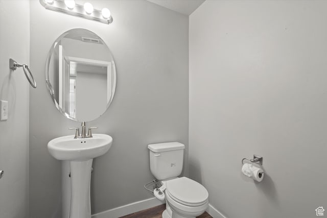 bathroom featuring toilet, a sink, baseboards, and wood finished floors