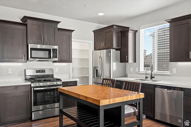 kitchen with dark wood-type flooring, a sink, stainless steel appliances, and dark brown cabinets