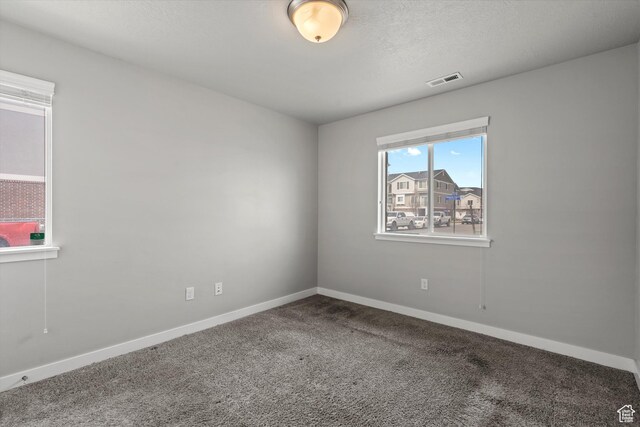 spare room with baseboards, visible vents, carpet floors, and a textured ceiling