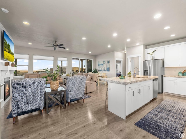 1352 E Abigail Ln, Eagle Mountain, UT 84005 - kitchen with appliances with stainless steel finishes, white cabinetry, sink, a center island with sink, and light hardwood / wood-style flooring