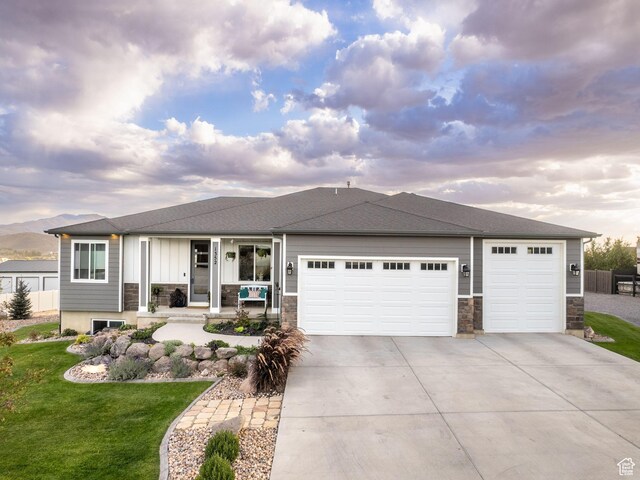 view of front of house with a garage, a lawn, and a porch