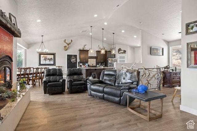 711 W Main St, Enterprise, UT 84725 - living room featuring vaulted ceiling, a fireplace, hardwood / wood-style flooring, a notable chandelier, and a textured ceiling
