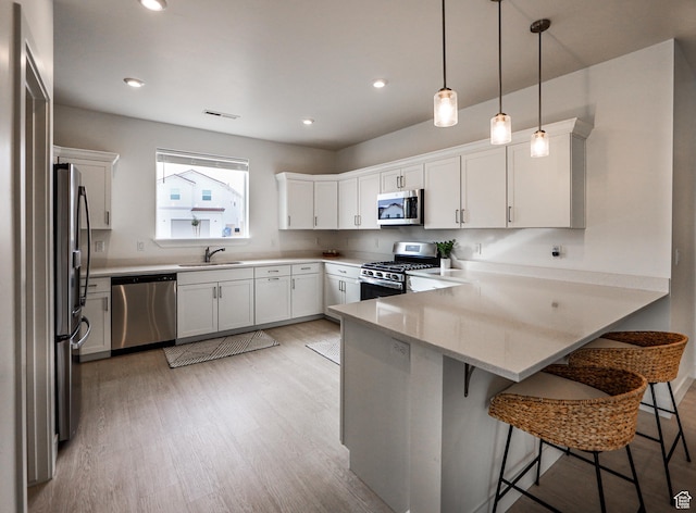 651 W Owen Dr, St George, UT 84790 - kitchen featuring appliances with stainless steel finishes, white cabinetry, hanging light fixtures, and kitchen peninsula