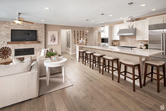 6187 W Wapiti Ridge Ln Unit 334, Herriman, UT 84096 - living room featuring wood-type flooring, a stone fireplace, ceiling fan, and a textured ceiling