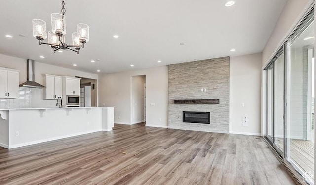 6187 W Wapiti Ridge Ln Unit 334, Herriman, UT 84096 - unfurnished living room featuring an inviting chandelier, a fireplace, and light hardwood / wood-style floors