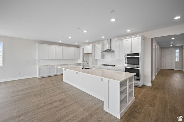 6187 W Wapiti Ridge Ln Unit 334, Herriman, UT 84096 - kitchen featuring a kitchen island with sink, white cabinetry, wall chimney exhaust hood, black gas stovetop, and stainless steel double oven