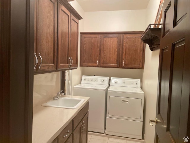 clothes washing area featuring cabinets, washing machine and dryer, sink, and light tile patterned floors